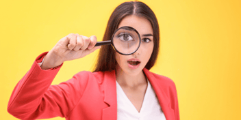 Woman looking through a magnifying glass at the camera