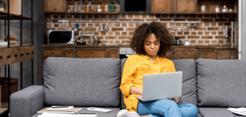 young woman sitting on sofa using laptop computer to develop a budget