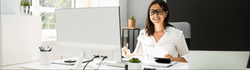 smiling woman sitting at a desktop computer