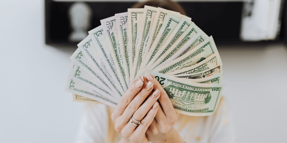 Woman holding cash in both hands and forming a fan