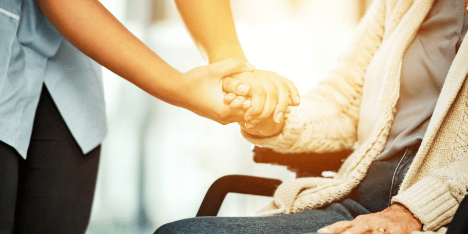 Holding hands with elder in wheelchair