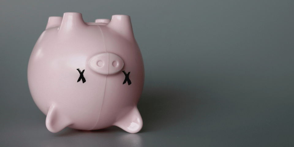 Piggy bank that is upside down with exes on his eyes