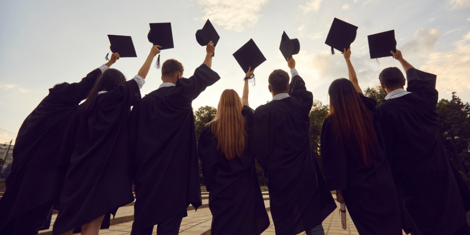 Graduates holding up their graduation caps